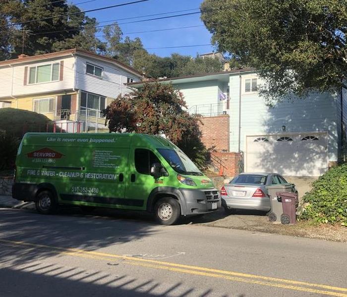 A SERVPRO van parked on the road in front of a home. 